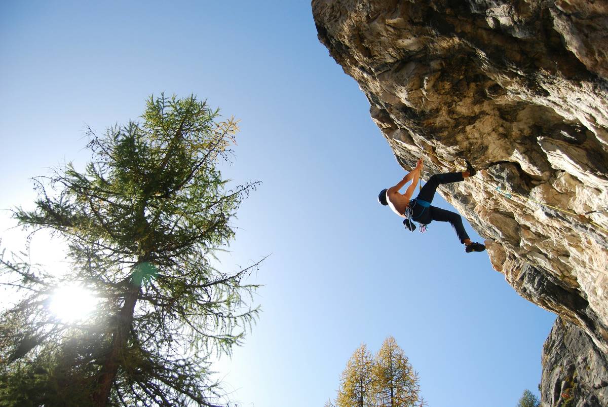 Close-up of hand placing a metal climbing hex into a vertical crack, demonstrating correct crack stopper gear locking technique