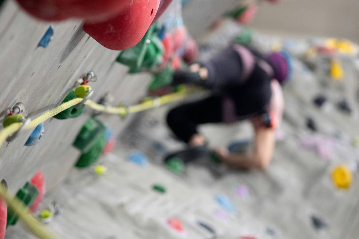 Close-up of climber using a hex placement tool to insert a climbing hex into a rock fissure